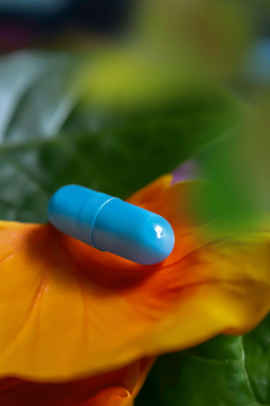 a blue pill sitting on top of a green leaf
