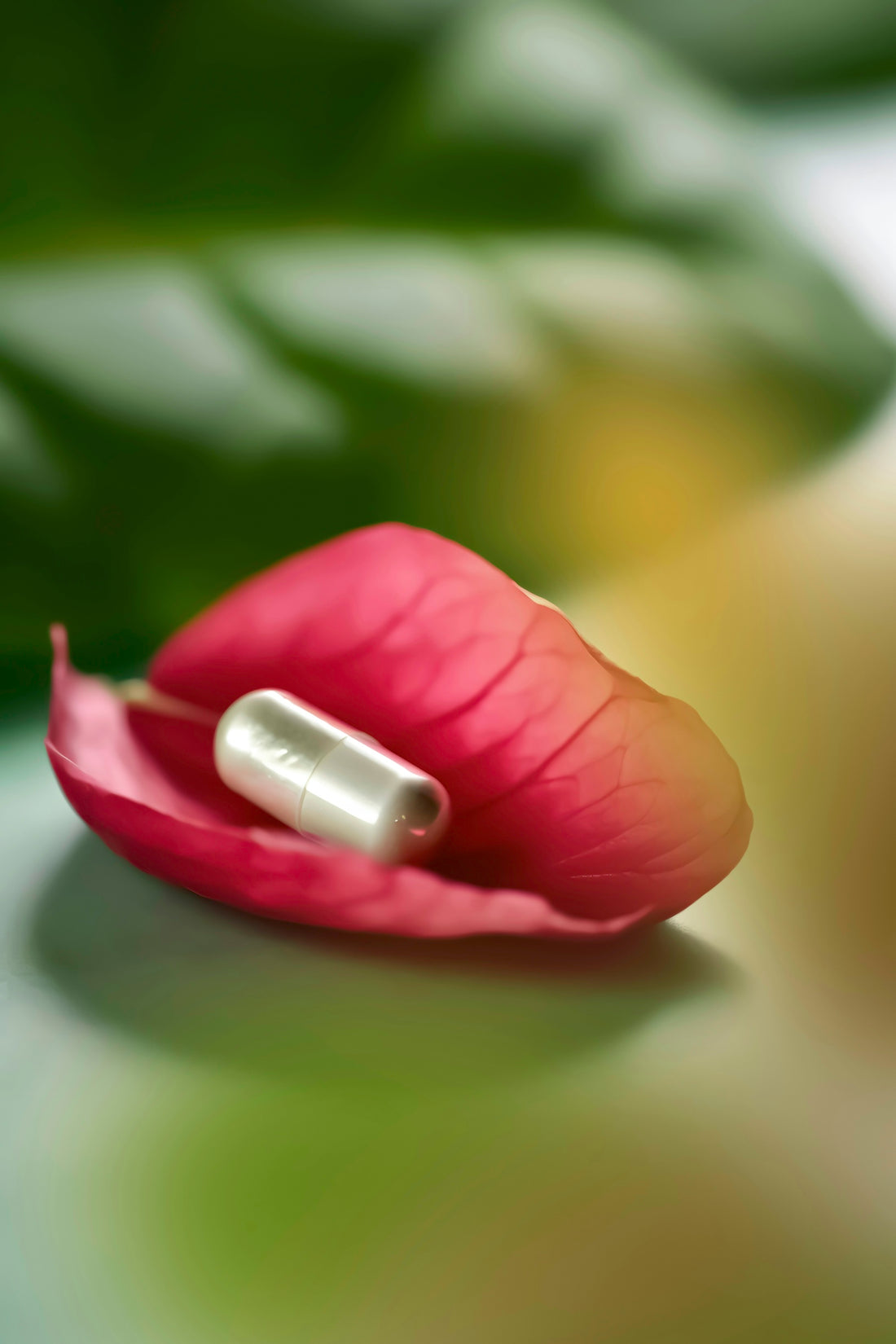a pill sitting on top of a pink flower