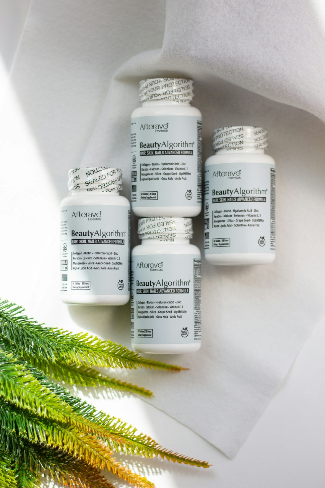 Four bottles of vitamin supplements sitting next to a plant