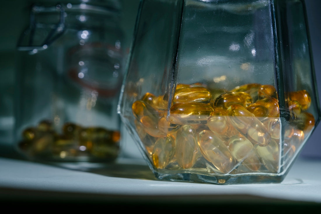 A glass jar filled with yellow pills sitting on top of a table