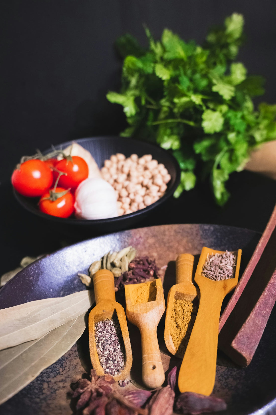 Spices, tomatoes, garlic, and chickpeas arranged for cooking.
